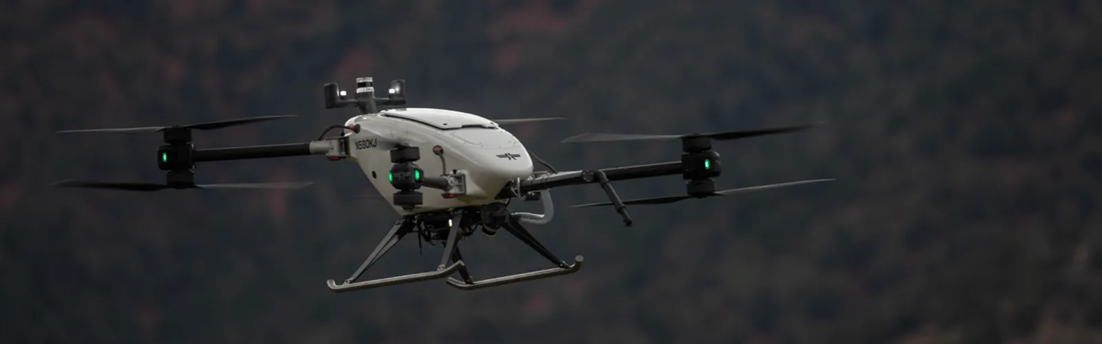 A small drone, featuring a white and black design, is captured mid-flight against a bright sky
